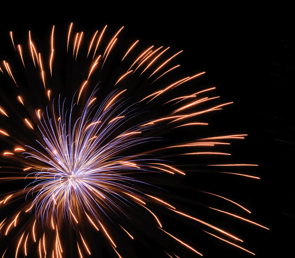 Bluish burst of fireworks inside reddish-yellow streaks from previous burst, off center