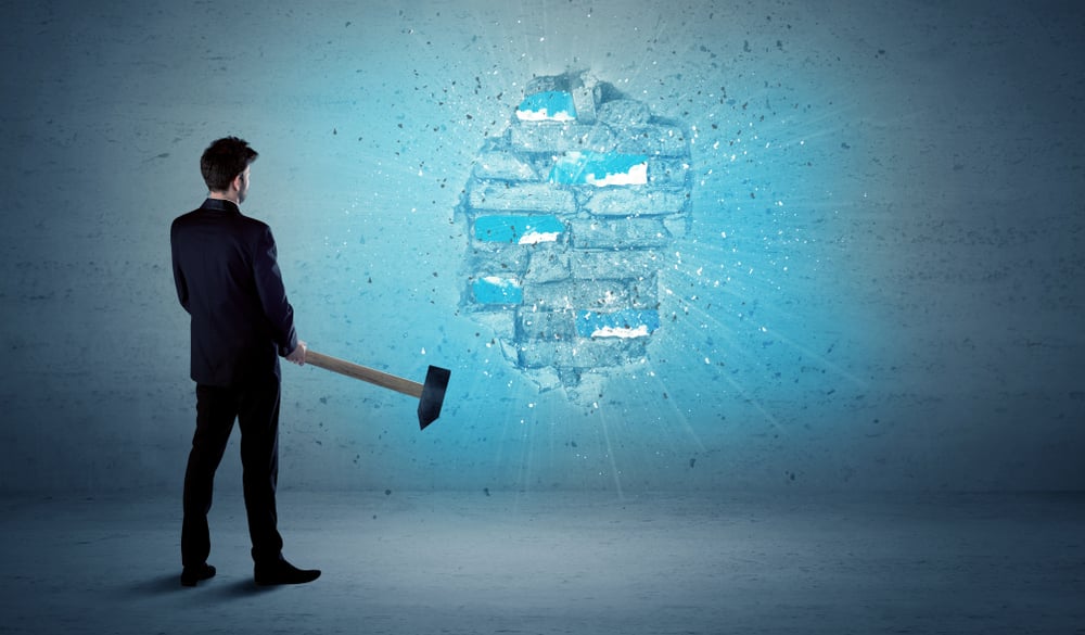 Business man hitting grungy brick wall with huge hammer