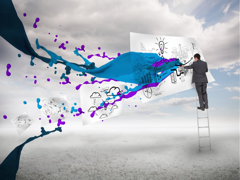 Businessman drawing on a paper next to paints splash with blue sky on the background