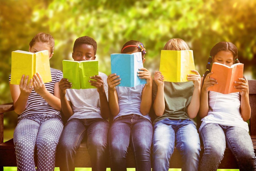 Children reading books at park against trees and meadow in the park-2