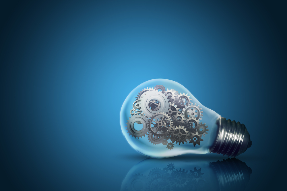 Close up of light bulb with gear mechanism inside isolated on dark blue background