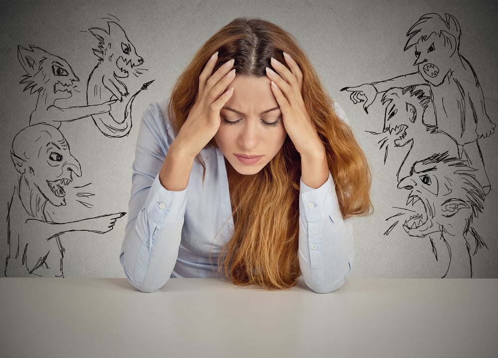 Evil Men pointing at stressed woman. Desperate young businesswoman sitting at desk in her office isolated on grey wall background. Negative human emotions face expression feelings life perception-1