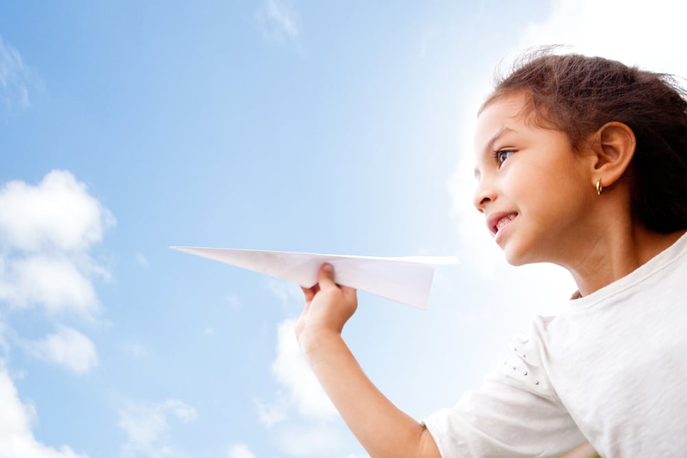 Girl holding a paper airplane and dreaming aboyt flying