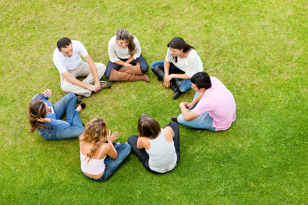 Group of friends sitting down in a circle outdoors