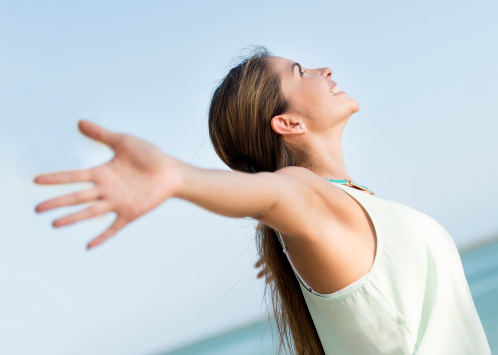 Happy casual woman with open arms outdoors