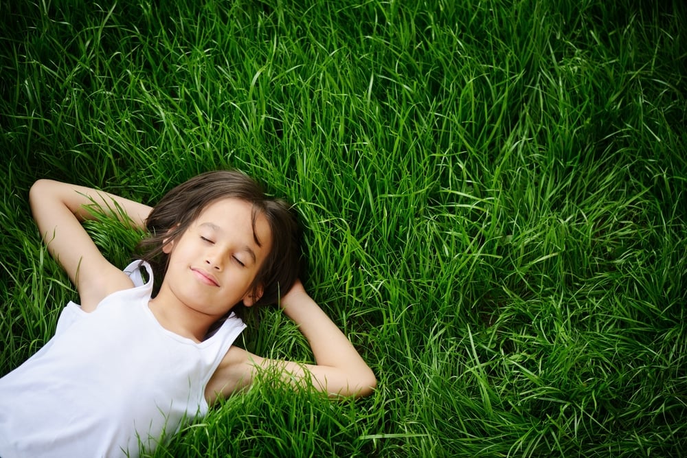 Happy child enjoying on grass field and dreaming