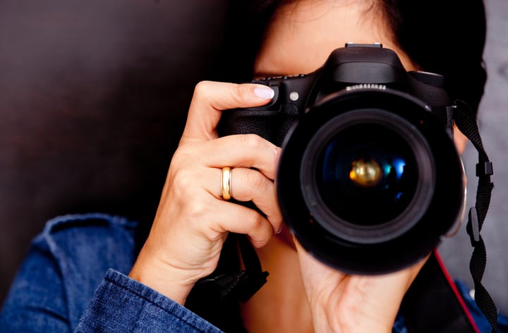 Portrait of a photographer covering her face with the camera-1