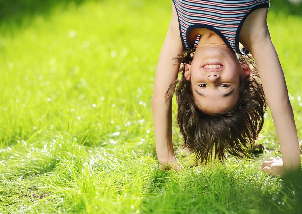 Portraits of happy kids playing upside down outdoors in summer park