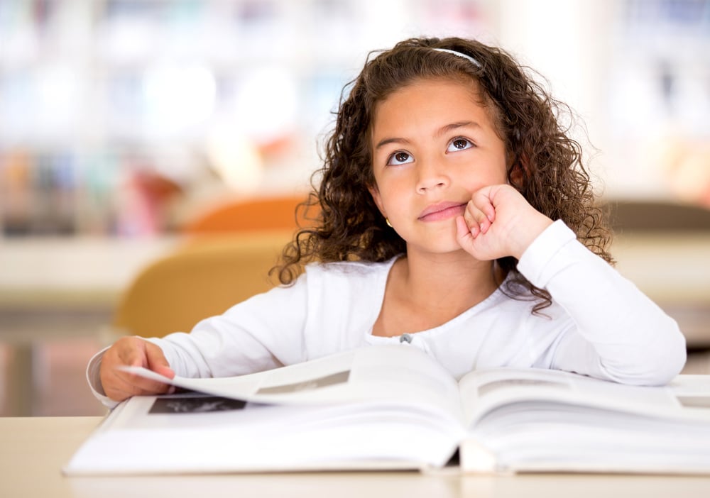 Thoughtful girl reading a book and using her imagination