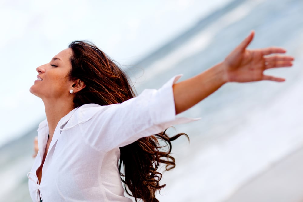 Woman relaxing at the beach with arms open enjoying her freedom-1