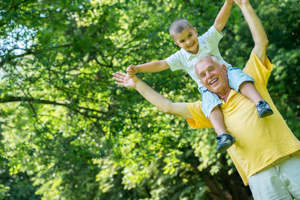 happy grandfather and child have fun and play in park on beautiful  sunny day